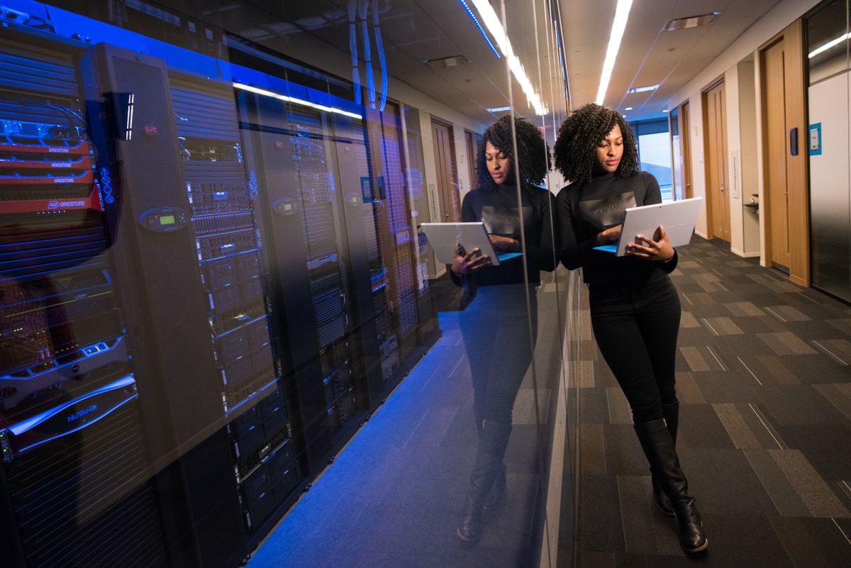 A woman using a laptop navigating a contemporary data center with mirrored servers representing saas api load testing before launch infrastructure testing