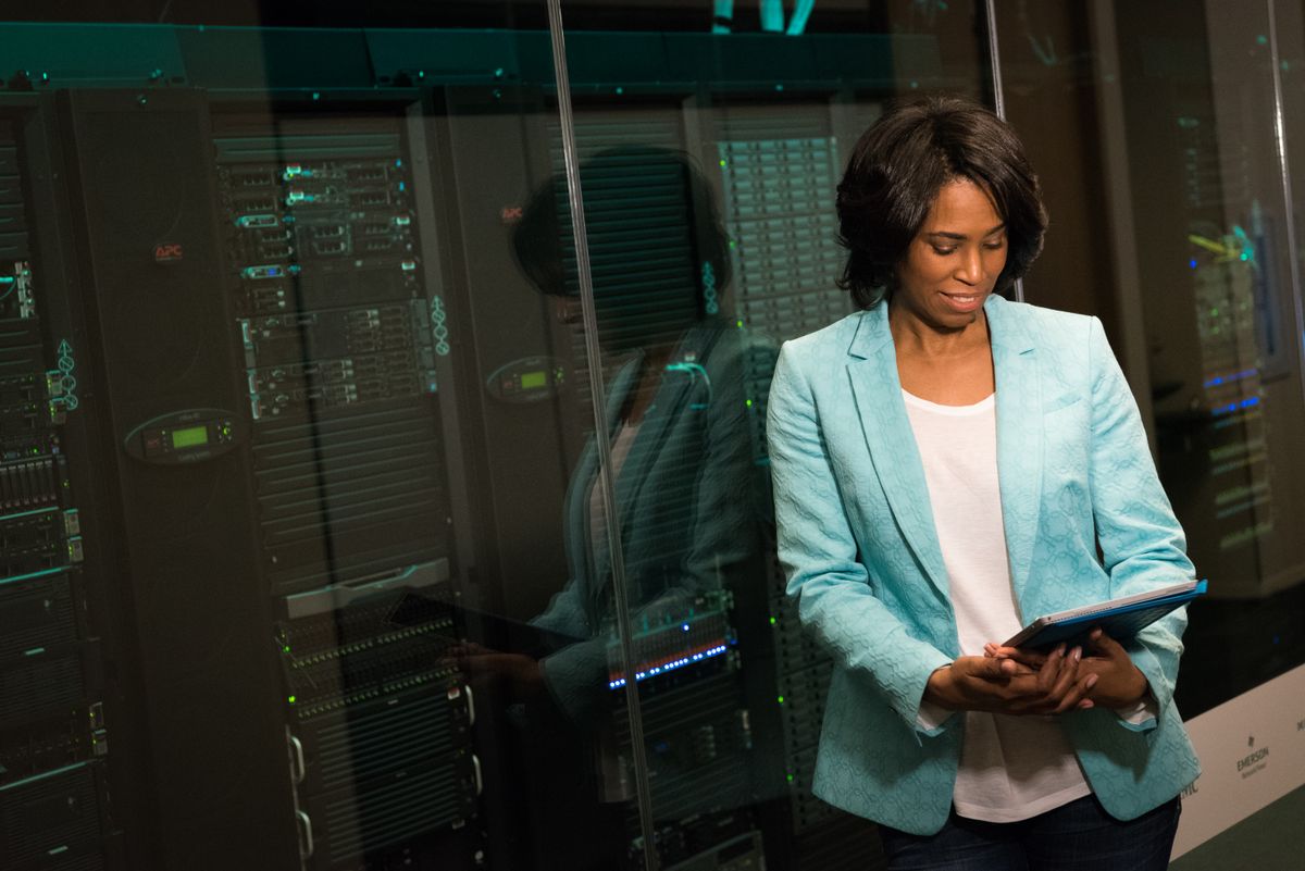 An IT professional examining data servers in a modern data center setting, representing the robust infrastructure behind queue systems