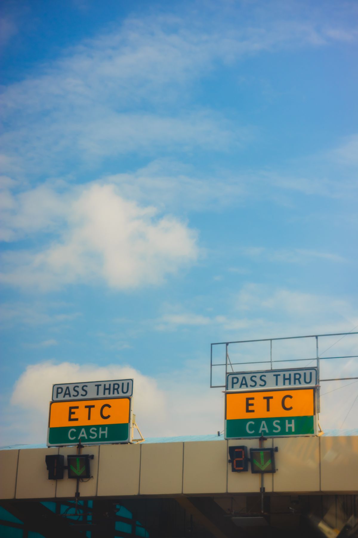 An automated toll plaza on a highway with multiple lanes narrowing into checkpoints, representing a connection pooler regulating traffic before it reaches the database