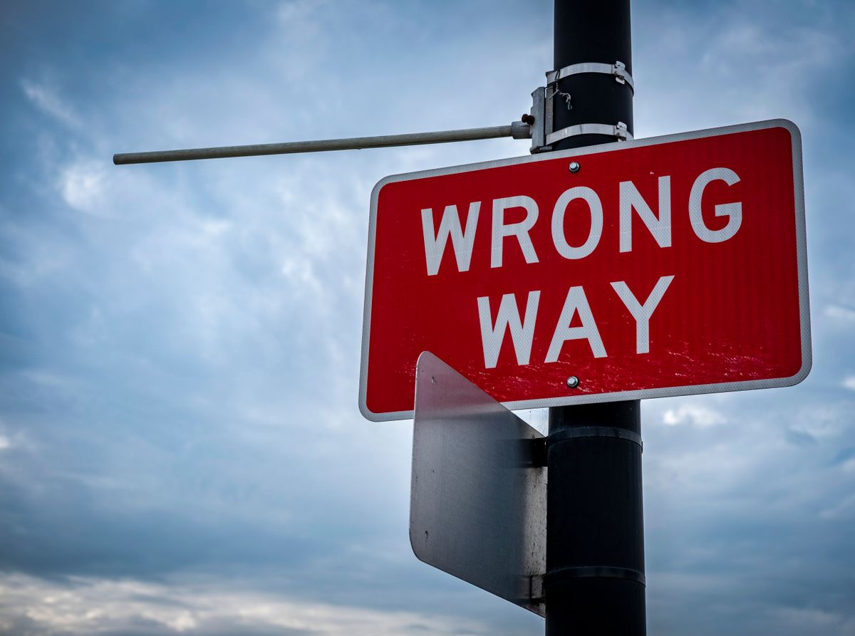 A red 'Wrong Way' road sign mounted on a pole against a cloudy sky, representing Cloudflare Pages configured to look for build output in the wrong directory