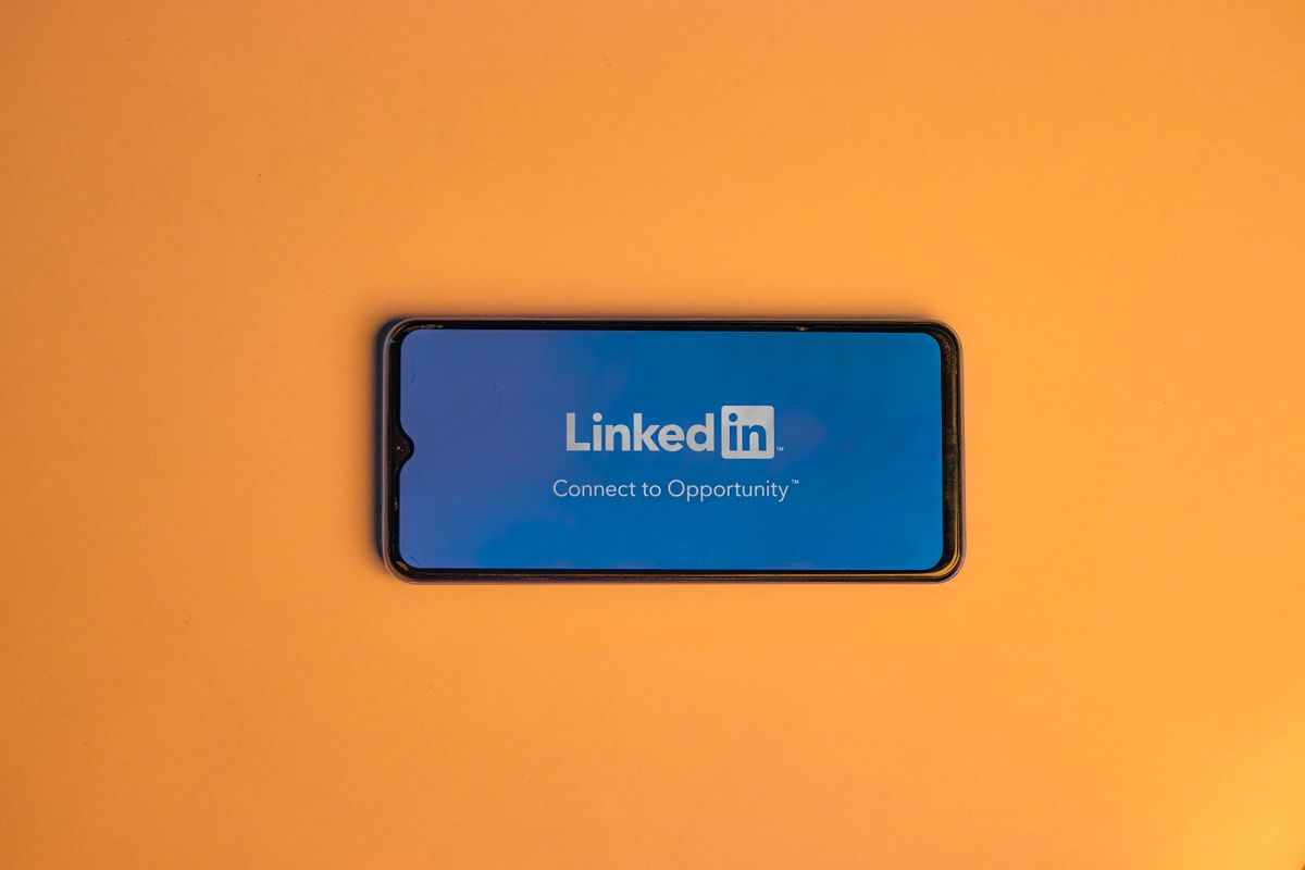 LinkedIn OAuth2 authentication integration — smartphone showing LinkedIn login on a vibrant orange background