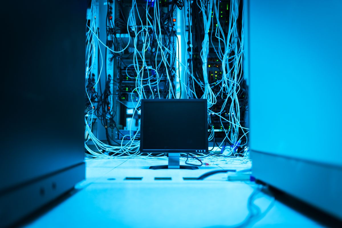 A complex network of cables in a data center with server equipment, representing the infrastructure behind audit log storage