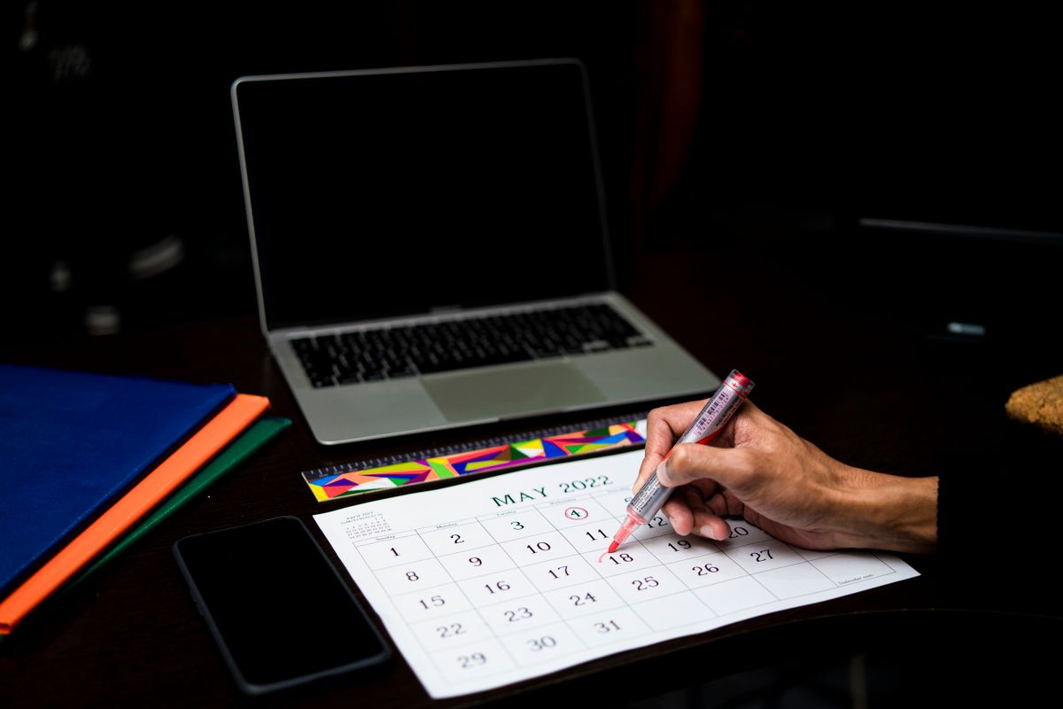 A person marking a date on a desk calendar next to a laptop, representing the verification step of confirming a revalidation actually reached every running replica, not just the one that happened to answer first