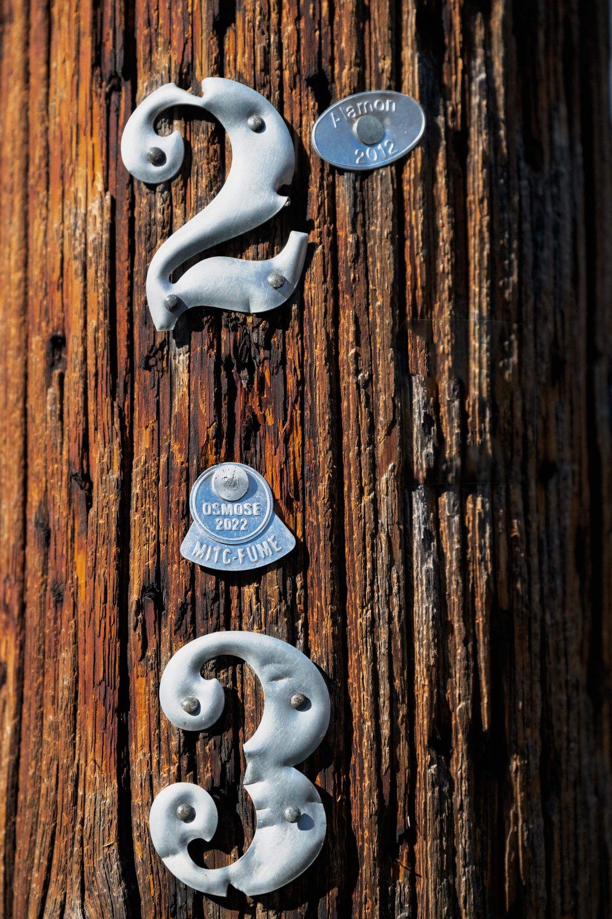 Metal number plaques nailed permanently to a wooden pole, representing the genuinely stable, hardcoded scheduler ID that keeps a repeatable job from drifting into duplicates