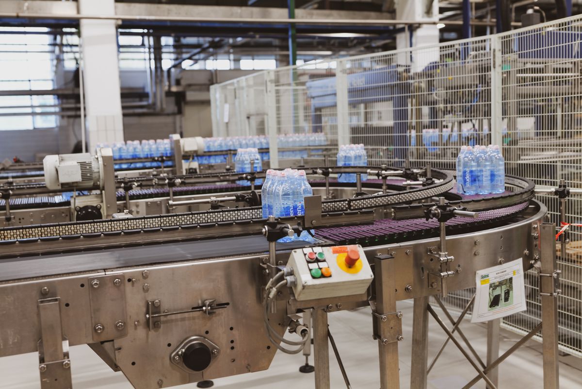 Water bottles moving along an automated conveyor belt in a modern factory, representing the generated client being produced fresh on every build instead of assumed to already exist