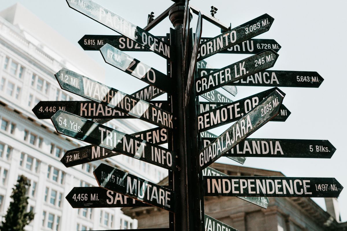 A directional signpost showing multiple city names and distances, representing the architecture decision that needs making early, before a frontend grows around an assumption that turns out to be wrong