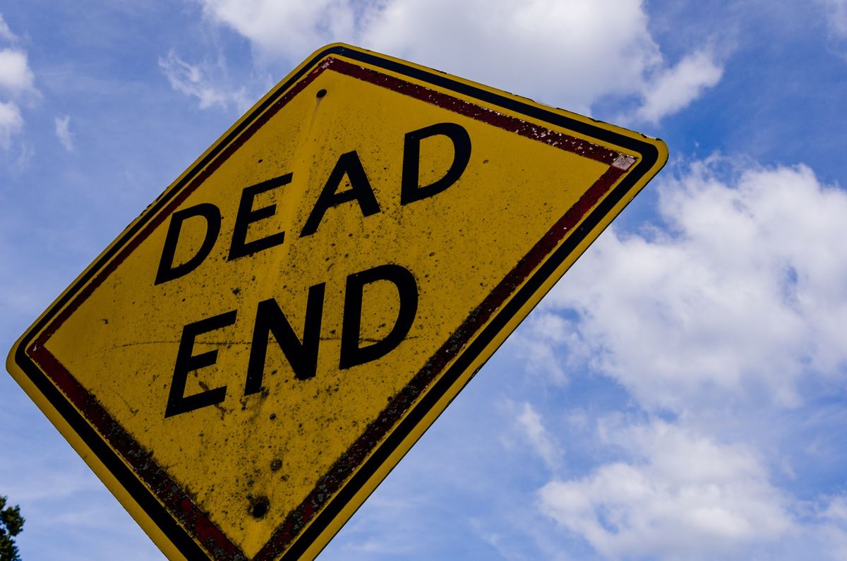A yellow dead-end road sign against a clear blue sky, representing a processor file path that resolved correctly in development but leads nowhere once the code is compiled and containerized