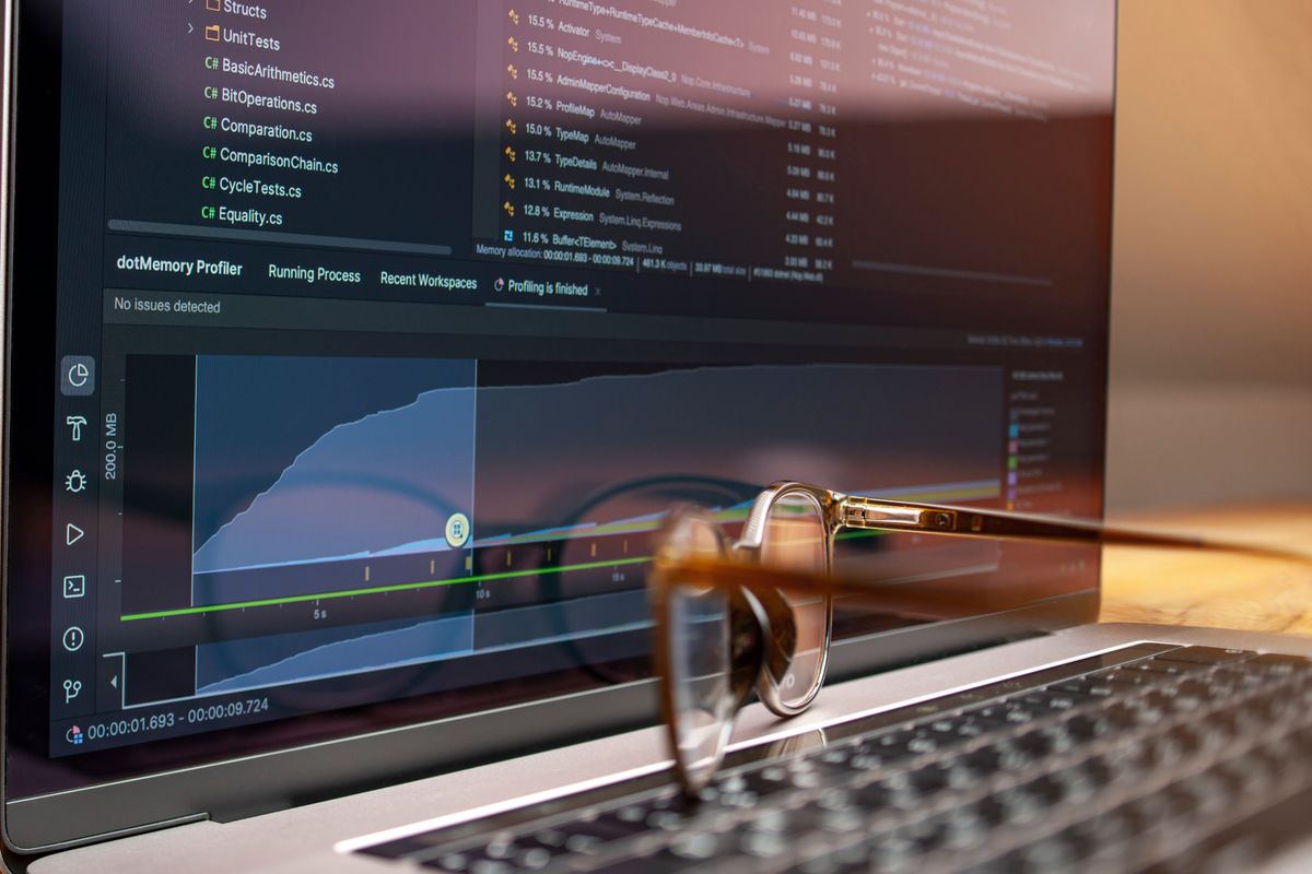 A developer working on a laptop with code and performance graphs
