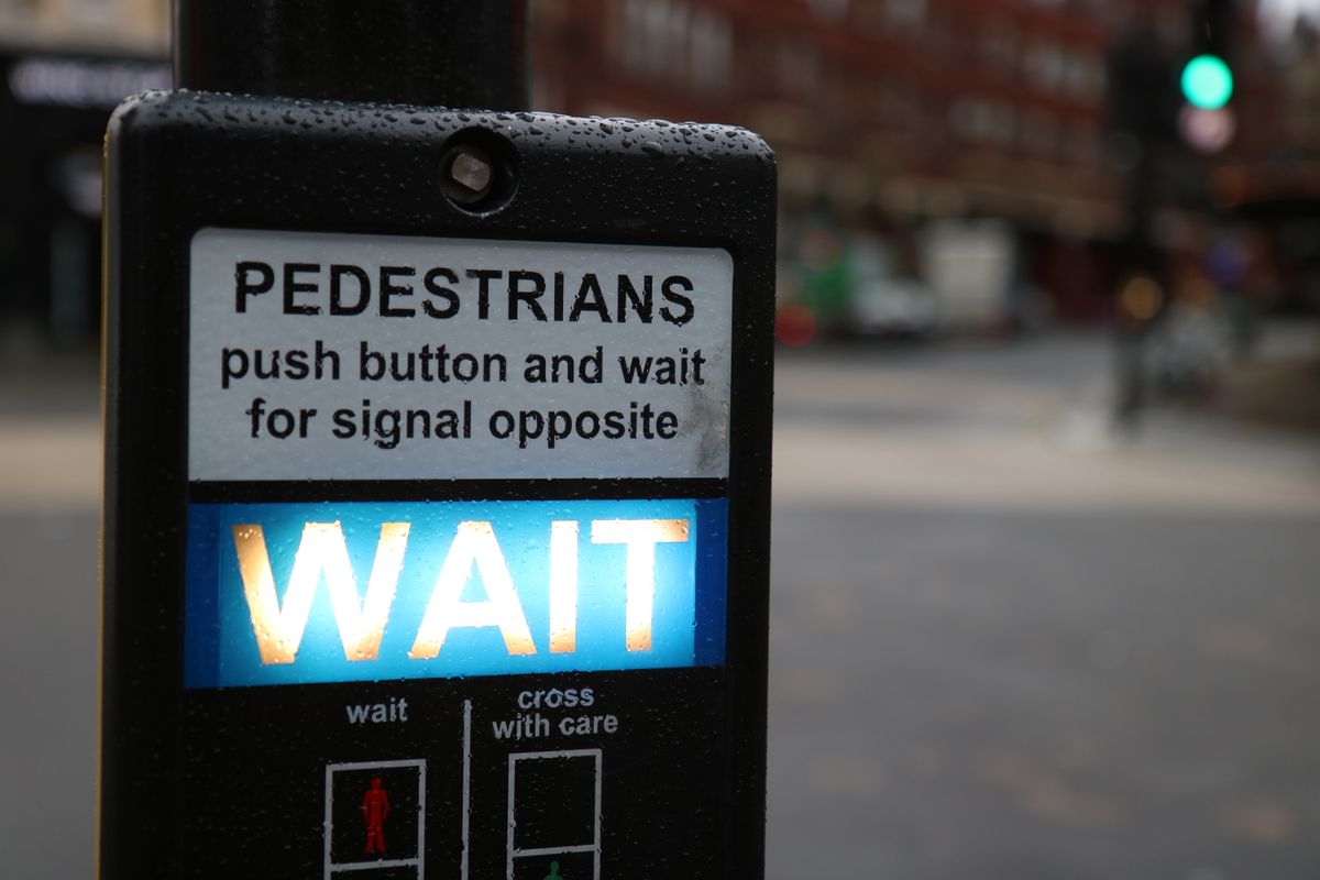 A pedestrian crossing signal glowing with the word 'WAIT' in bright letters, representing the await now required before reading params or searchParams in Next.js 15