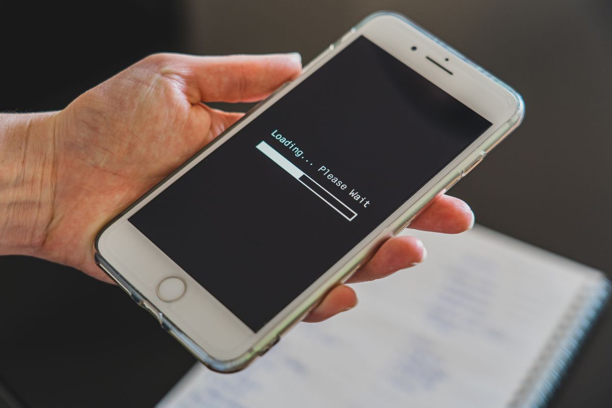 PostgreSQL performance optimization for a SaaS dashboard — a phone showing a loading spinner, representing a slow dashboard
