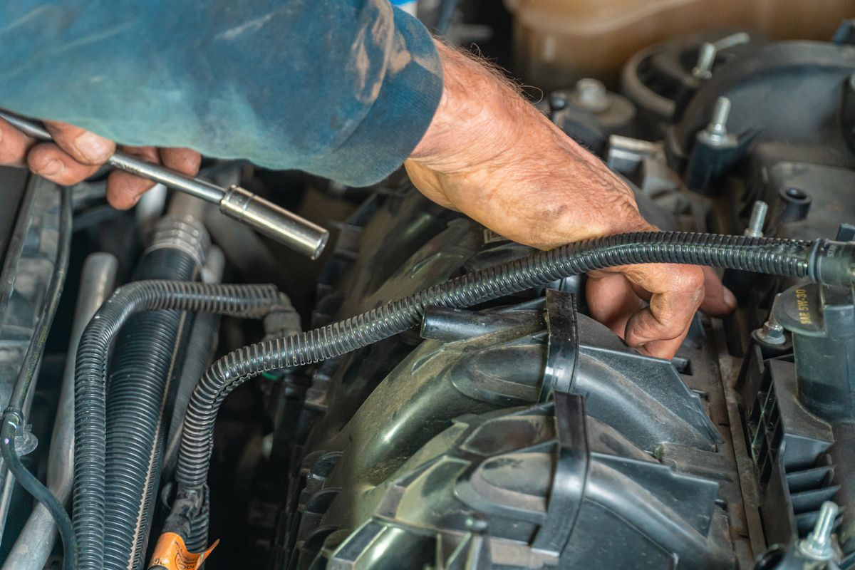 A mechanic's hands working directly on a car engine, representing a schema change made straight against production without going through the usual migration process