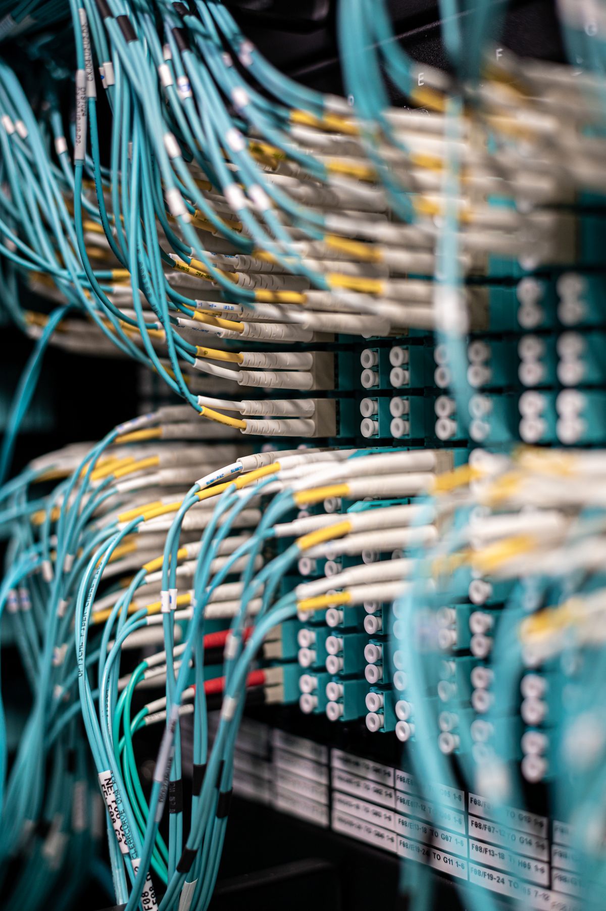 Rows of blue cables plugged into a server patch panel in a data center, representing Railway's private network between services