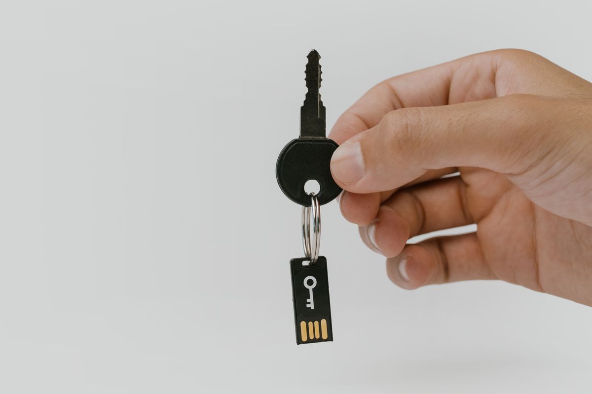 NestJS API key authentication SaaS implementation concept — a hand holding a physical key attached to a USB drive, representing secret credentials