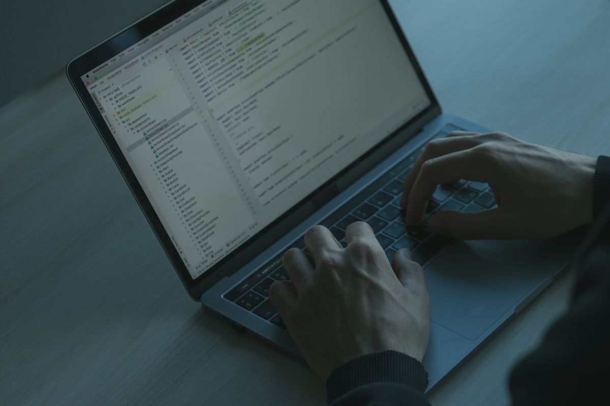 Developer coding NestJS JWT refresh token authentication with Passport.js on a laptop focused on cybersecurity