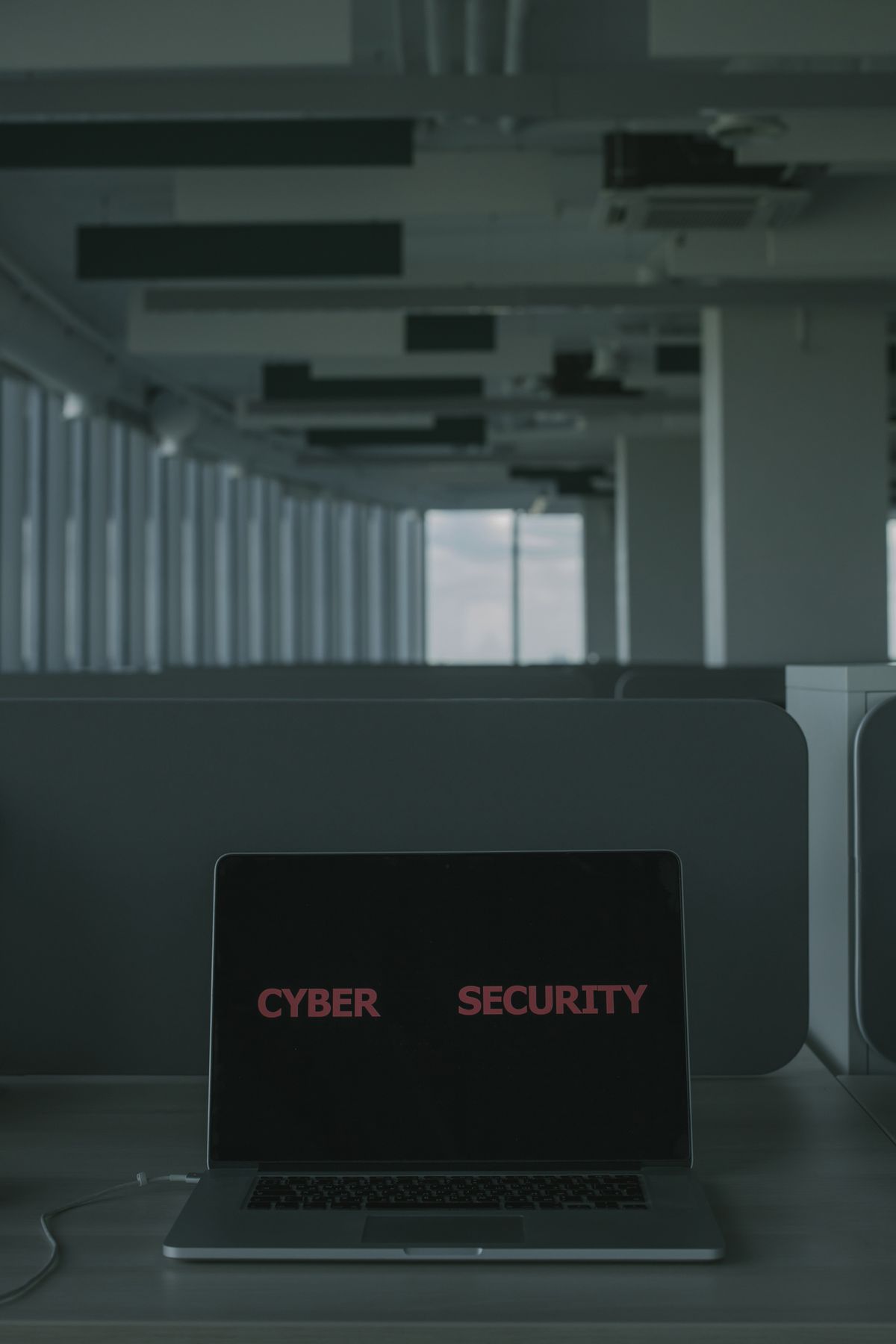 A laptop displaying 'Cyber Security' concepts in a modern office setting