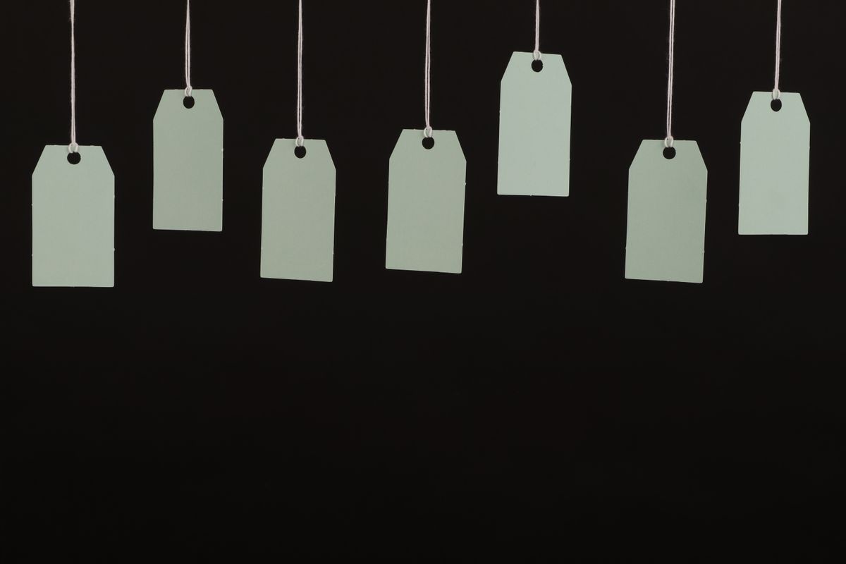 Several blank green tags hanging on strings against a black background, representing placeholder values swapped for the real environment variable the moment a container actually starts