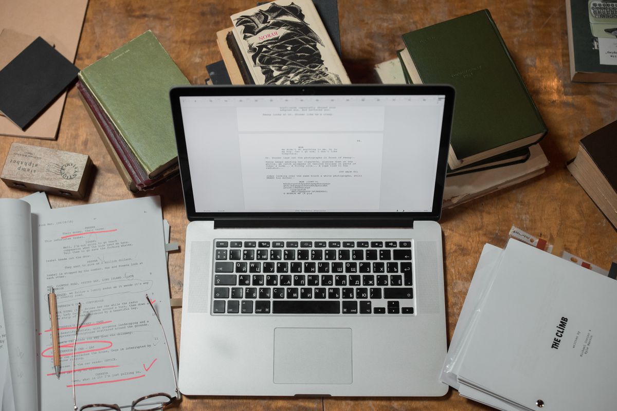 SaaS public developer API documentation and SDK development — a laptop surrounded by reference books representing API docs and SDKs