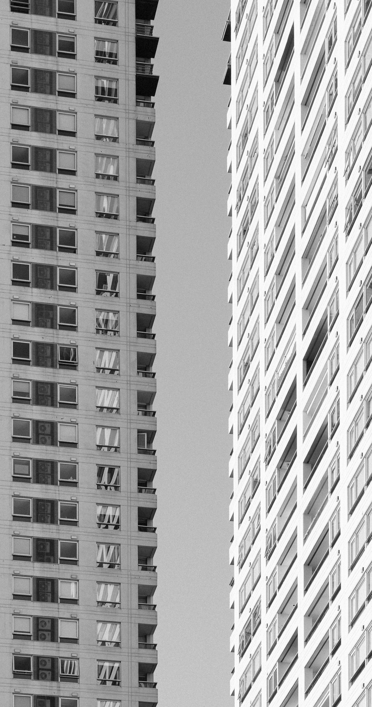 Two grayscale high-rise buildings standing apart from each other, representing a web service and a worker service that need to be deployed as two genuinely separate things on Render